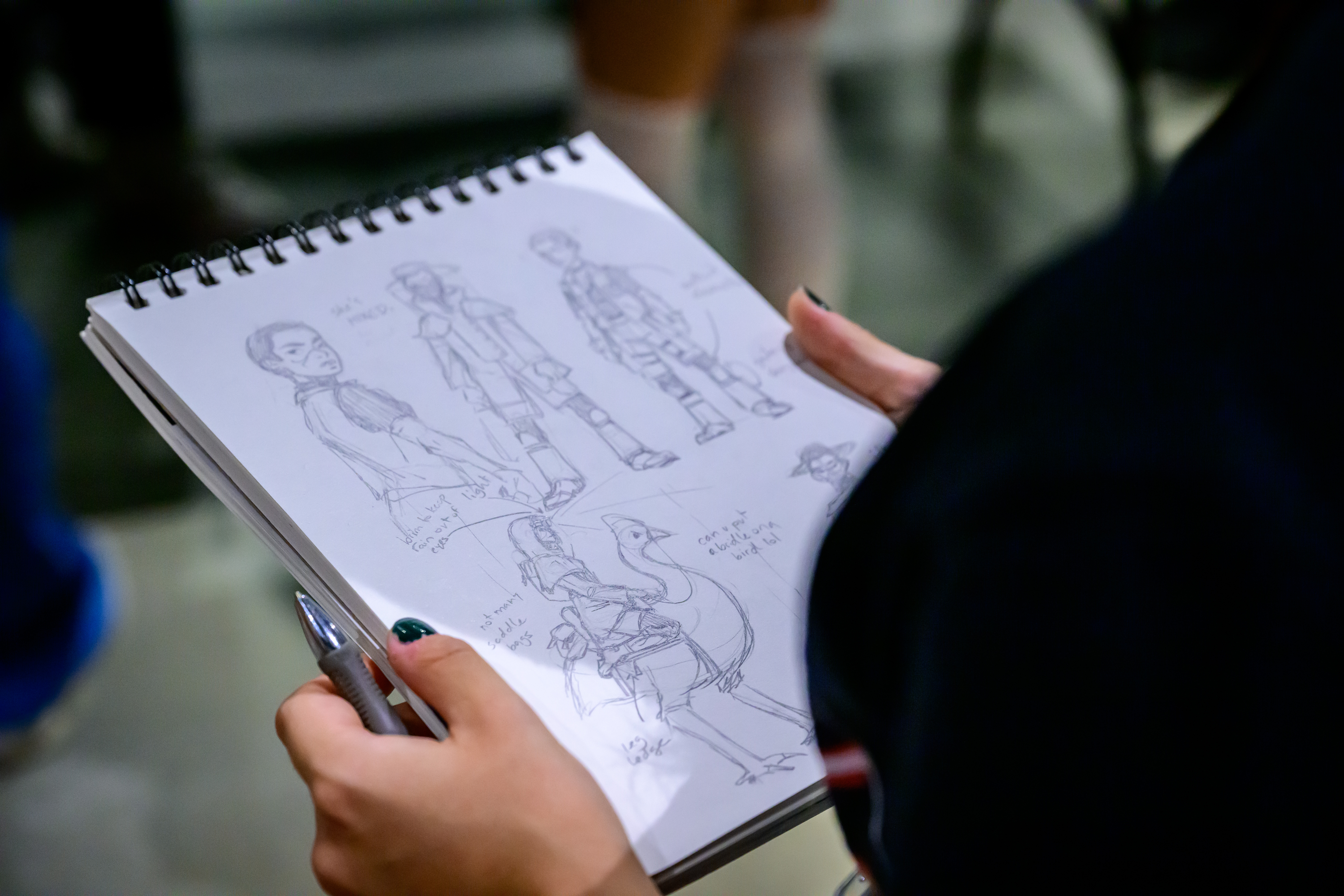 someone holding up a sketchpad with drawings