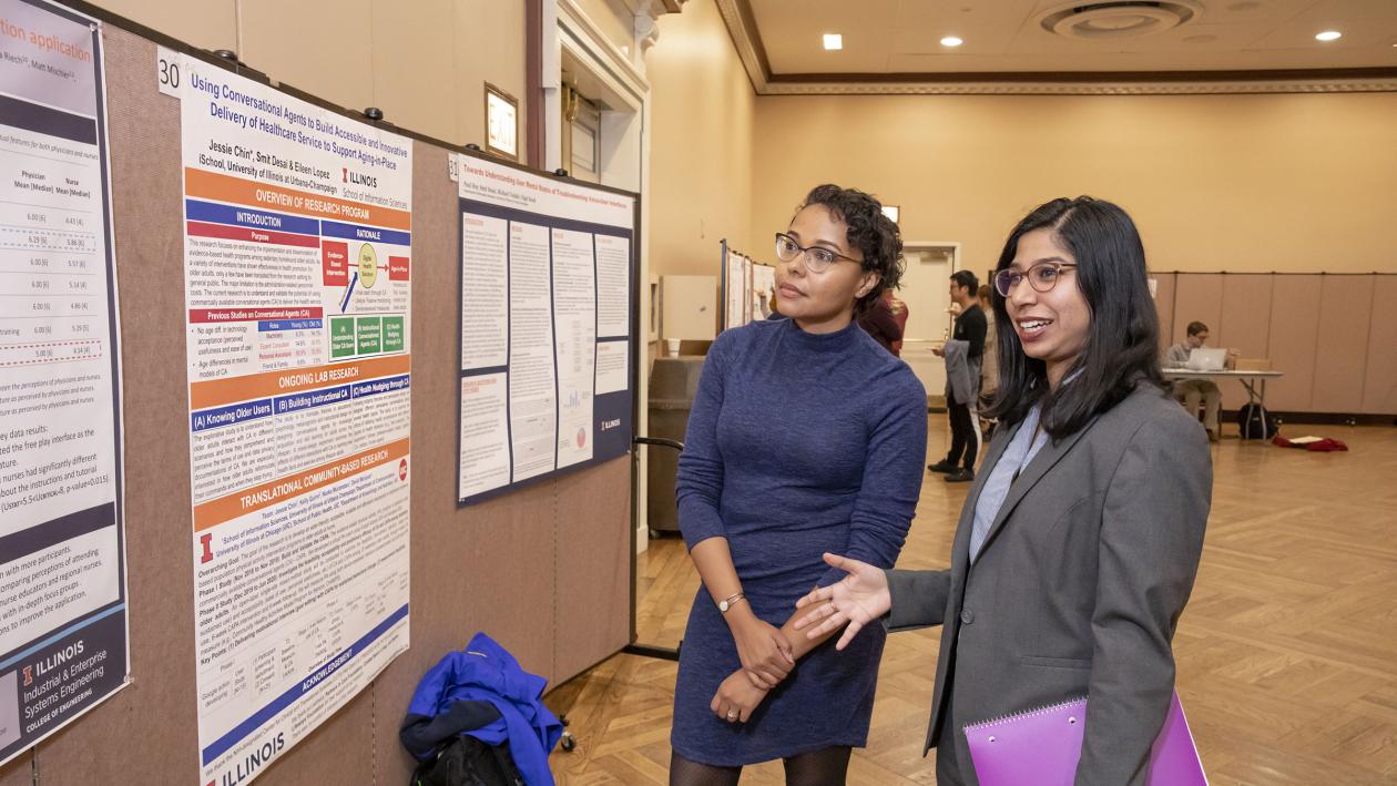 two students discussing poster at research showcase