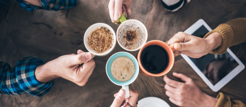 Overhead shot of four people 'cheers'-ing cups of coffee