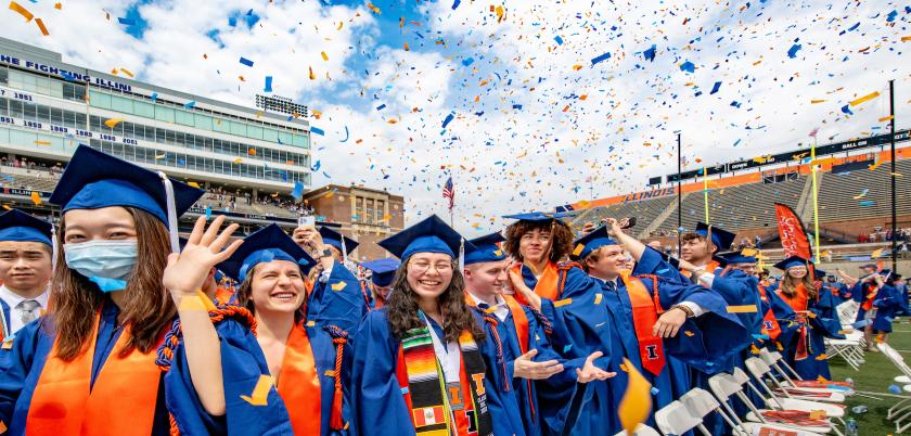 Photo of Illinois graduates during commencement with confetti in their air.