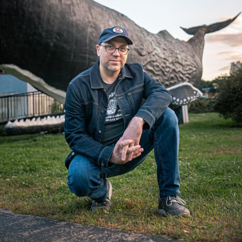 Daniel Kraus in front a full-sized whale statue