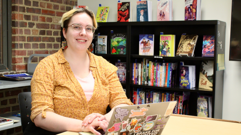 Fi Keane smiling while working on her laptop at The Center for Children's Books.