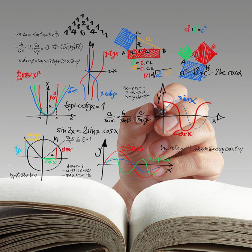 open book with someone's hand writing math and science formulas