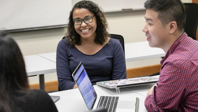 student smiling in classroom with laptop
