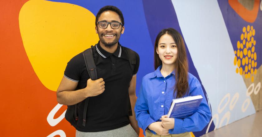 two students stand in the multipurpose area of the Hub building