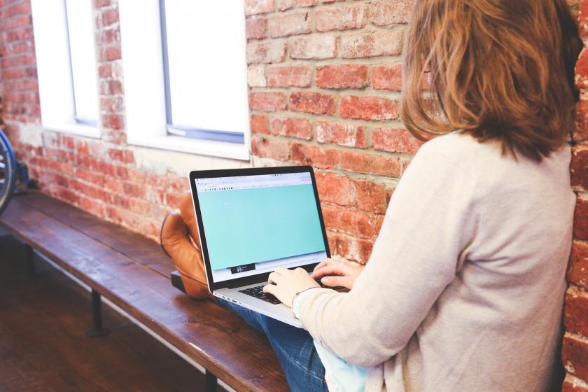 Woman with laptop and brick background