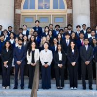 Business Intelligence Group (BIG) student consultants smile on the steps of Foellinger Auditorium with Associate Professor Yoo-Seong Song
