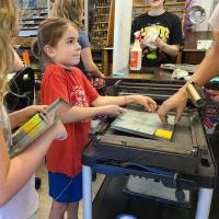A camper participates in printmaking during summer camp at the Champaign-Urbana Community Fab Lab.