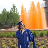 Nicky Martin makes a puckering face in his regalia in front of an orange fountain at Hailene Gateway.